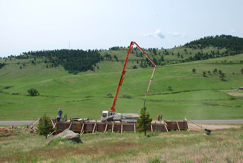 A view of the concrete pump truck looking south over the building site. Workers are waiting for the last concrete truck to arrive.