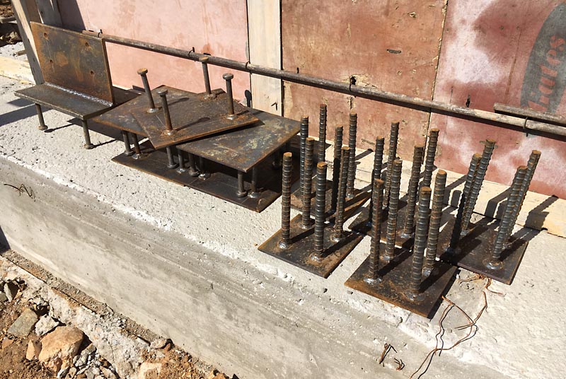 These steel plates were embedded in the wet concrete on the top of the walls. Brackets for various timber frame elements will be welded to these plates when the timber frame is erected.