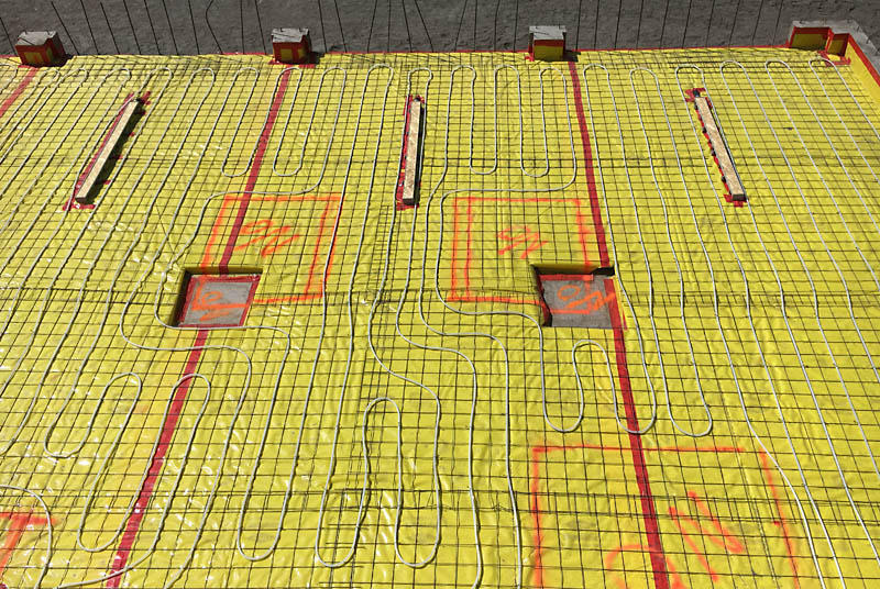 Here is another picture before concrete. The 6'–long trench drains are covered with plywood caps to keep the concrete out. The areas outlined in paint in the center of the photo with "NO" in them are exclusion zones that will let me bolt an auto lift to the floor in an area clear of the radiant heat tubing.