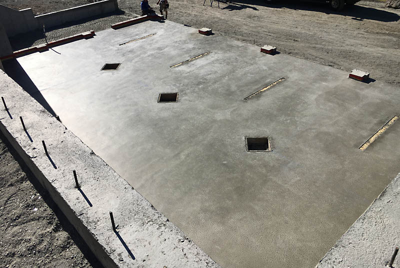 The slab has been poured. The three diamond–shaped cutouts provide access to footings for steel posts that will support a beam running the length of the garage. Once the posts are set, the voids will be filled with concrete and surround the posts.