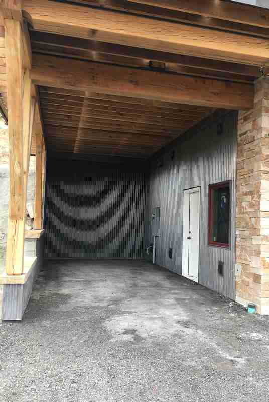 The carport interior walls are clad in A606 7/8" corrugated steel panels. This steel will develop a rust patina on the surface. Also visible are the 4" thick capstones on the outside retaining walls. These haven't been mortared in place yet. The green pipe on the right is a drain for the roof gutters that leads to daylight down the hill.