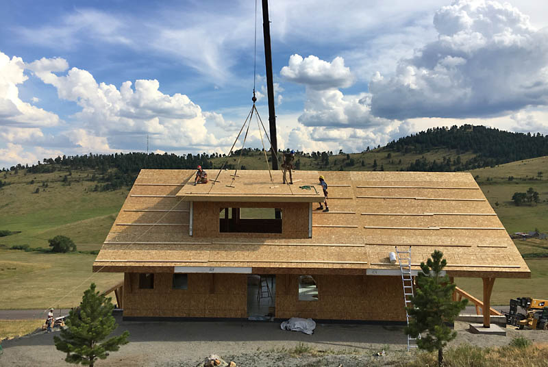 Harris, Alan and Matt set the last roof panel on the north side, finishing up the 3/12 pitch shed dormer. Alan is the owner of Wind River Timberframes.