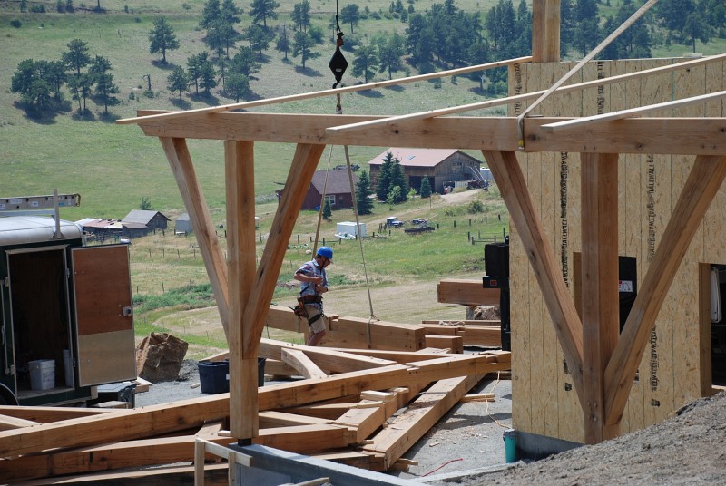 The beam for the east carport is temporarily held in place with 2 x 6 boards. The posts are supported by a knife plate inlet into the end which in turn land on ¼" steel plate embedded in the concrete wall. This connection will be welded to secure it in place.