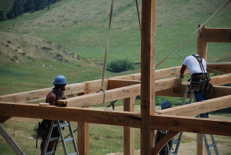 Jason and Jaime are setting a loft floor joist into place. Each end has a dovetail cut into it.