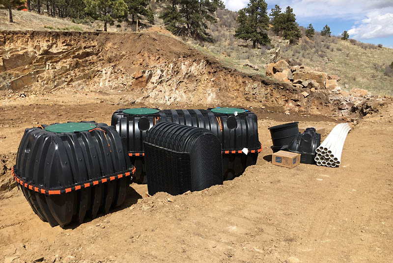  Two plastic tanks, one with two chambers, form the holding tank system. The stack of black plastic in the foreground is the half-dome pieces that are used in the leach field.