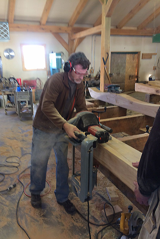 I worked with Darby for three days, cutting a variety of timbers. Here I'm using a portable bandsaw to cut a curve into a brace for a rafter in the living room. <span class='myGreyFont'>[End of series. <a href='../../index.html'>Return</a> to the New House page.]