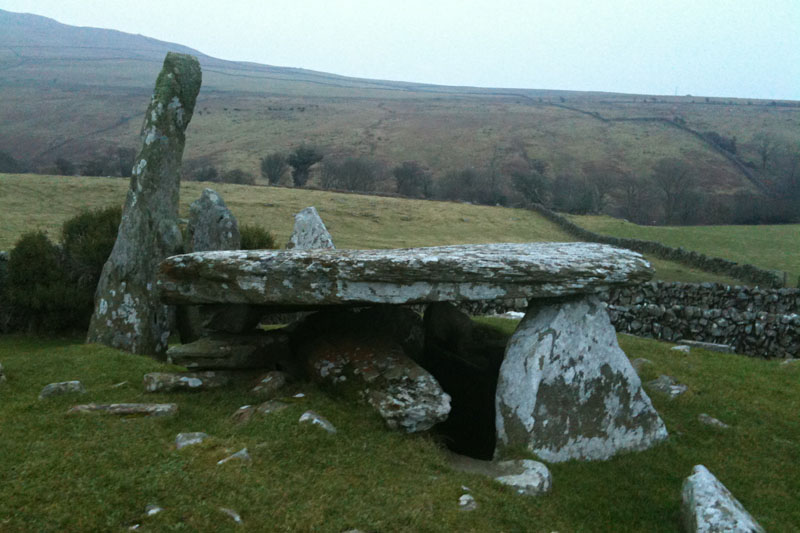 <h3>Cairnholy I & II</h3>A cap stone is visible from the back of Cairnholy II. Anthropologists found Neolithic tools, such as arrow heads and a flint knife in both tombs. A rare jadeite axe was found in Cairnholy I. Jadeite was sourced from the Alps and was a sign of wealth.