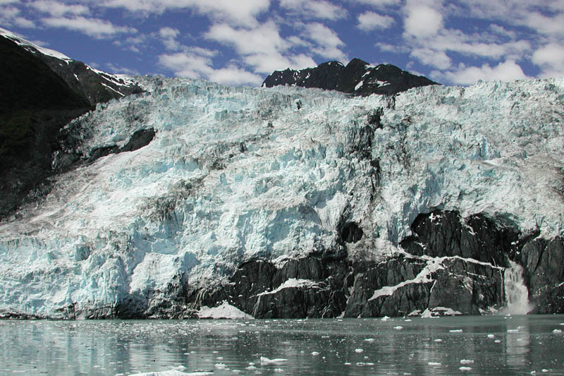 Most of the air bubbles in glacier ice have been forced out by the weight of the ice above. Ice absorbs red wavelengths, so the light that is reflected back has a lot of blue in it, giving the glacier ice it's characteristic color.